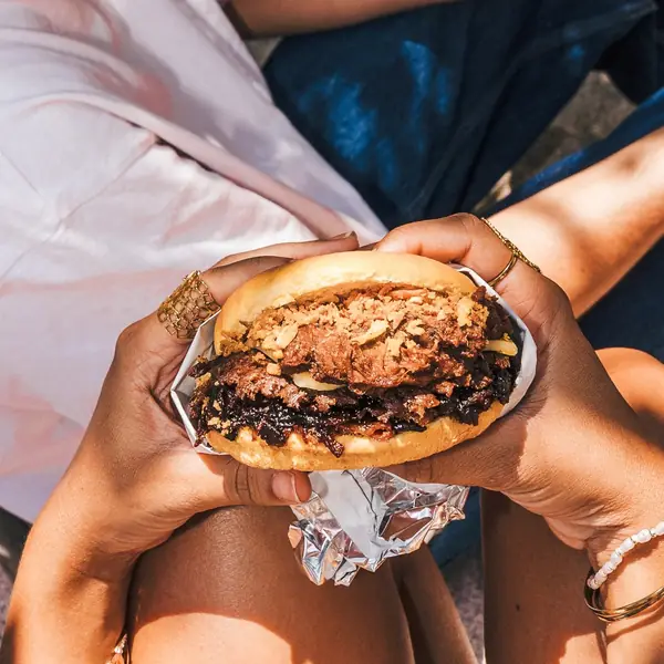 Dos manos sujetando una burger recién servida
