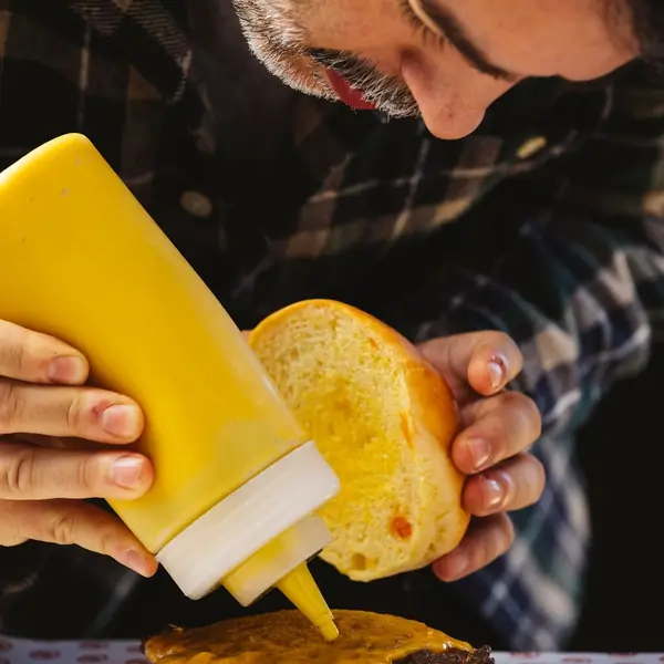 Mostaza cayendo sobre el pan de una burger en montaje